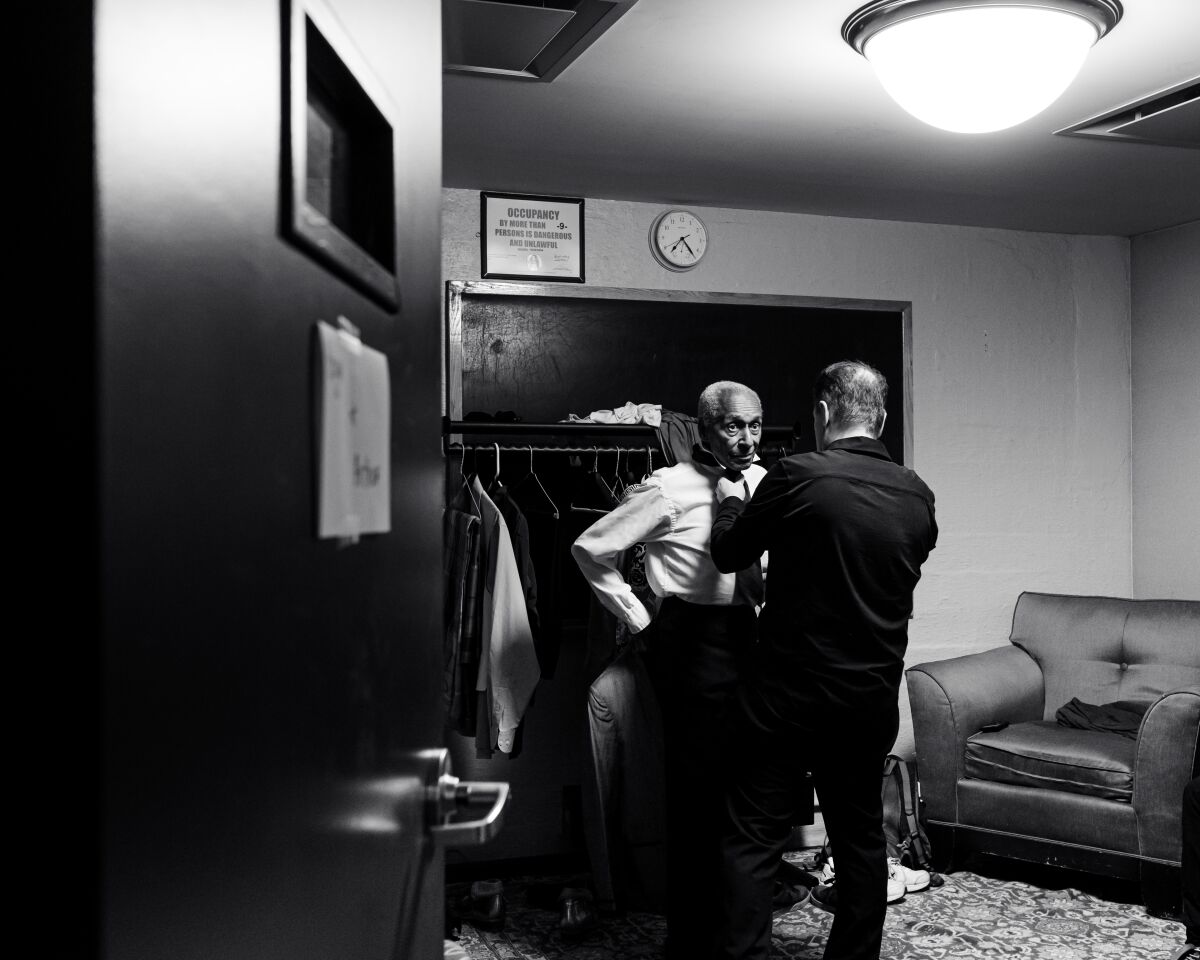 A man helps another man with his tie.