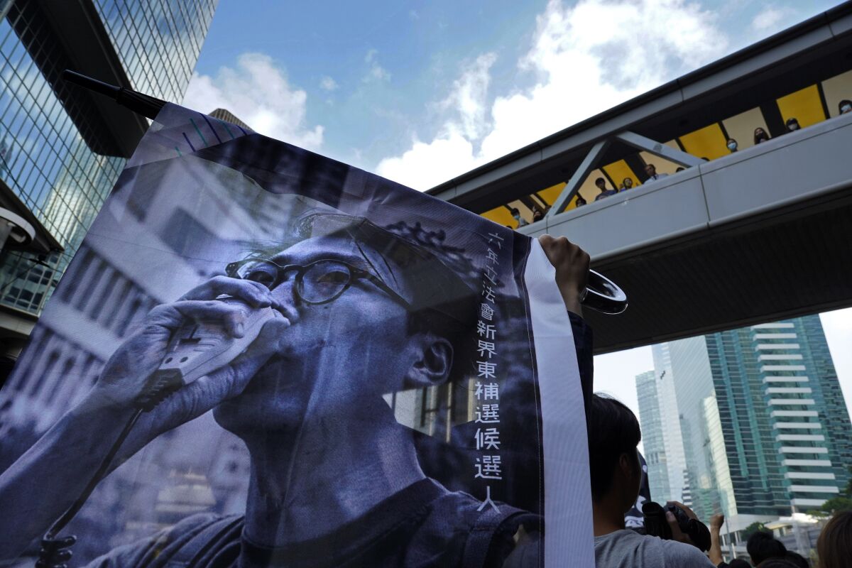 FILE - Supporters hold a banner with a picture of Hong Kong activist Edward Leung as they shout slogans outside the High Court in Hong Kong, on Oct. 9, 2019. Leung, who coined the now-banned slogan "Liberate Hong Kong, Revolution of our Times," was released from prison Wednesday, Jan. 19, 2022, after spending four years behind bars for rioting in 2016. (AP Photo/Vincent Yu, File)