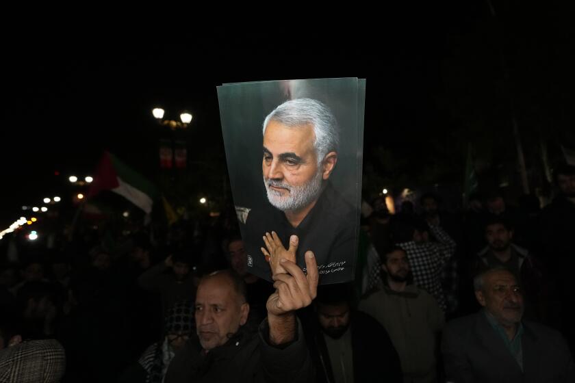 Un manifestante sostiene un cartel del fallecido general de la Guardia Revolucionaria iraní Qassem Soleimani, asesinado en un ataque de dron estadounidense en 2020 en Irak, en un acto contra Israel ante la embajada británica en Teherán, Irán, la madruga del domingo 14 de abril de 2024. (AP Foto/Vahid Salemi)