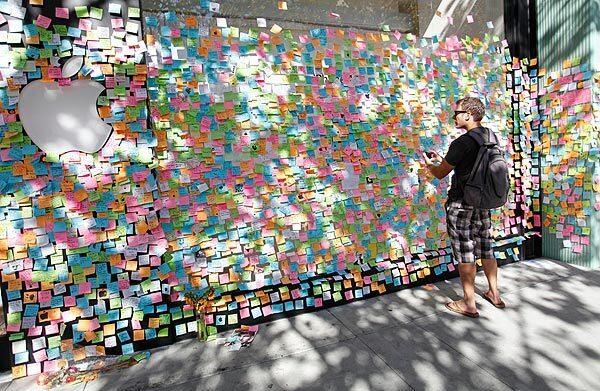 Ryan Mickle takes a picture of memorial notes placed in front of an Apple retail store in Palo Alto as the store is temporarily closed during the memorial service for Apple co-founder Steve Jobs on Oct. 19, 2011 in California. Apple stores across the country shut their doors for a few hours Wednesday to enable employees to participate in a staff celebration of the life of Jobs.