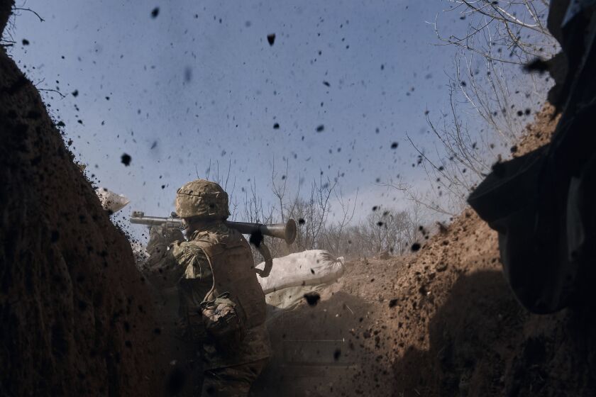 A Ukrainian soldier of the 28th brigade fires a grenade launcher on the frontline during a battle with Russian troops near Bakhmut, Donetsk region, Ukraine, Friday, March 24, 2023. (AP Photo/Libkos)