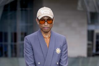 Pharrell Williams poses in periwinkle suit and Kenzo Paris baseball cap at the Louis Vuitton Foundation at the 2024 Olympics