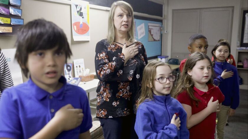 In this Monday, March 12, 2018, third grade teacher Lisa Sander says the pledge of allegiance with h