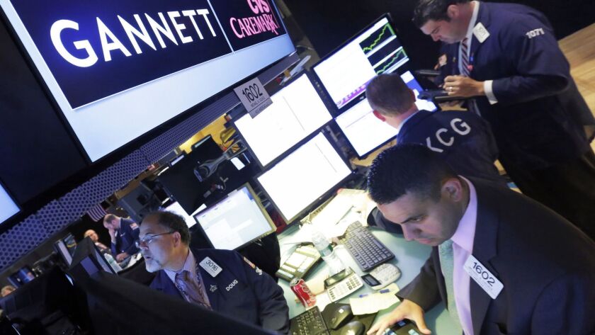 Traders work at the New York Stock Exchange post that handles Gannett Co. shares.