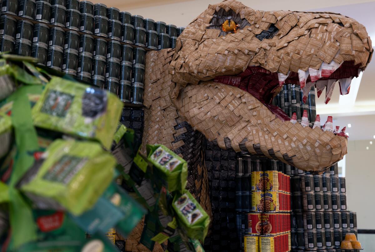 A sculpture, "Doing Our Jurassic Part to End Hunger," by AO is made of food that will be donated to the OC Food Bank.