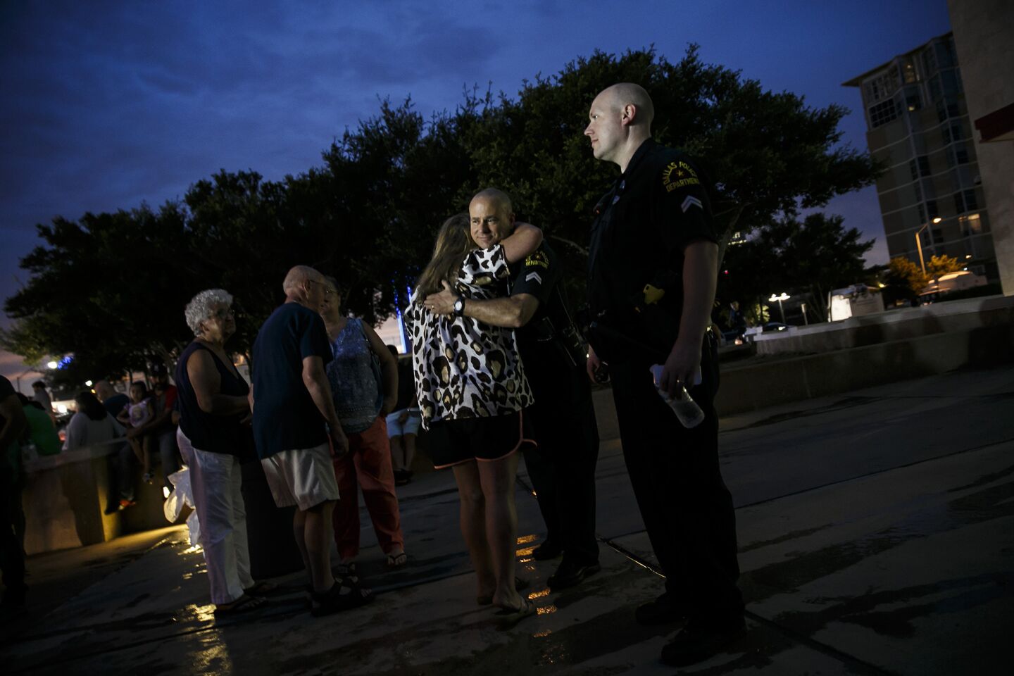People give hugs to Dallas police officers standing outside the memorial for slain officers in the recent attacks in Dallas.