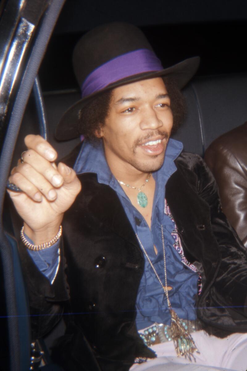 Jimi Hendrix is photographed in the back seat of a car. The date handwritten on the slide is October 8, 1971.