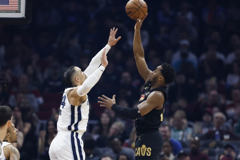 Cleveland Cavaliers guard Donovan Mitchell, right, shoots against Memphis Grizzlies forward Dillon Brooks during the first half of an NBA basketball game, Thursday, Feb. 2, 2023, in Cleveland. (AP Photo/Ron Schwane)