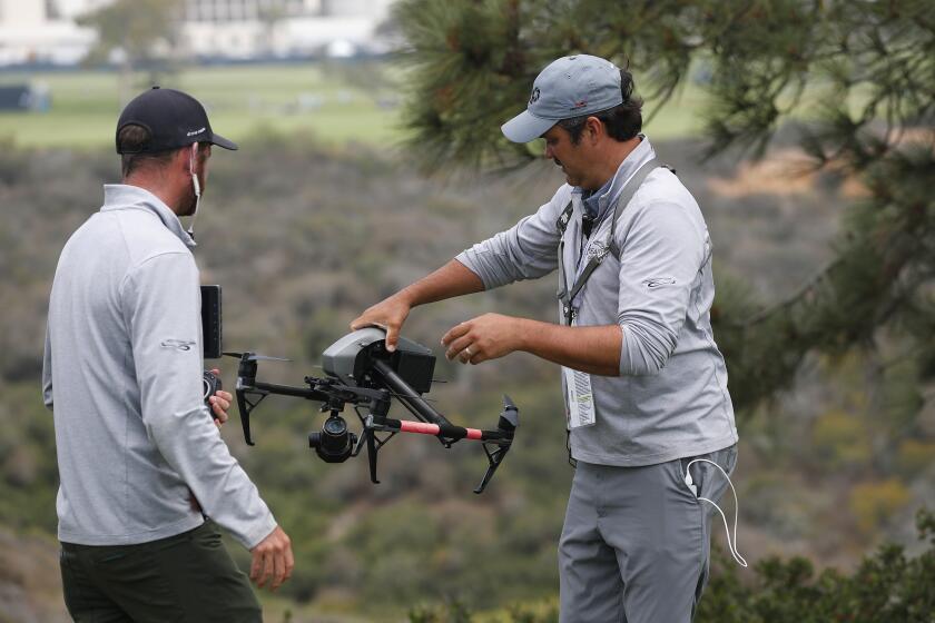 SAN DIEGO, CA - JUNE 16: Drone operator Ben McClung picks up a drone used for coverage of the U.S. Open at the Torrey Pines golf course on Wednesday, June 16, 2021 in San Diego, CA. Tanner Deprin, left, looks on. (K.C. Alfred / The San Diego Union-Tribune)