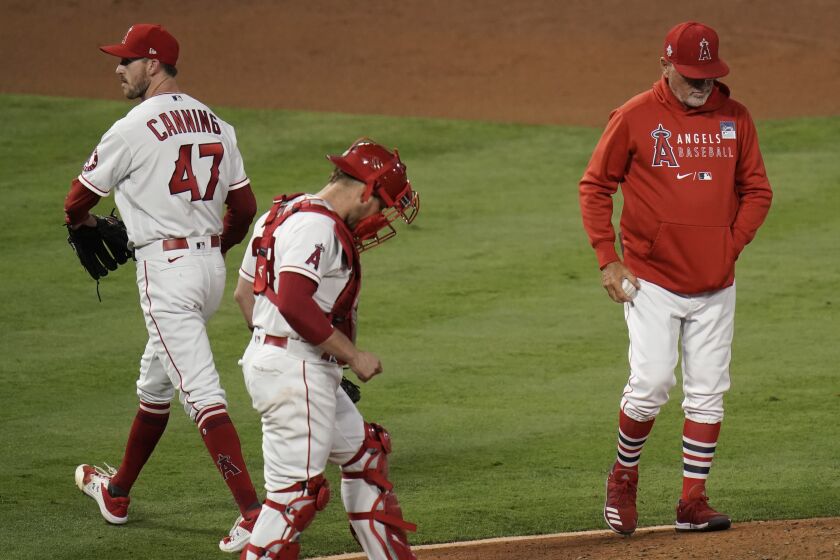Los Angeles Angels starting pitcher Griffin Canning, left, leaves the mound after he was removed by manager Joe Maddon, right, during the fourth inning of the team's baseball game against the Seattle Mariners in Anaheim, Calif., Thursday, June 3, 2021. (AP Photo/Jae C. Hong)