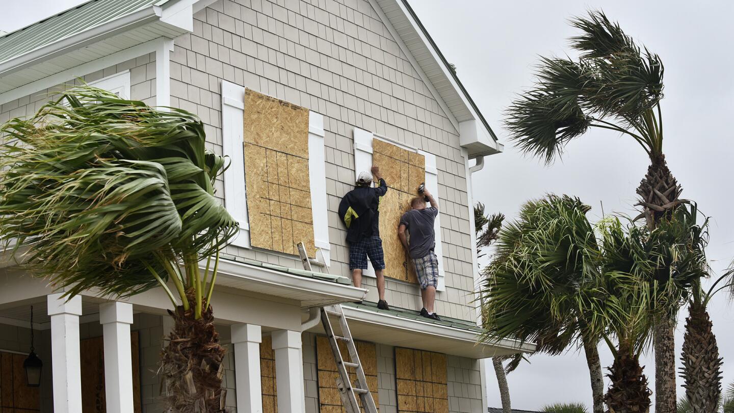 Workers from Armstrong Construction put plywood over windows of a home in preparation for Hurricane Matthew Wednesday, Oct. 5, in Ponte Vedra Beach, Fla.