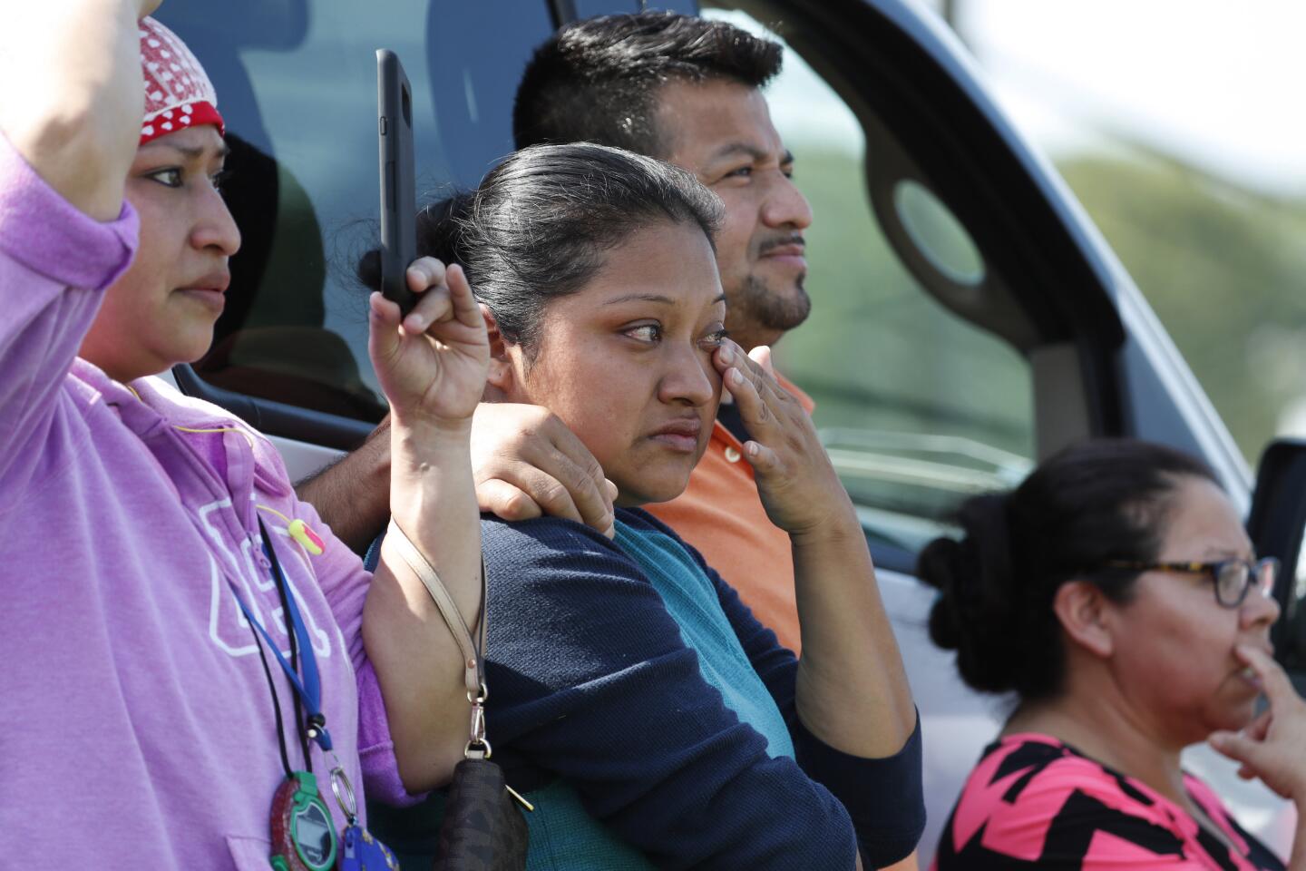 Friends, co-workers and family watch as U.S. immigration officials raid the Koch Foods Inc. plant in Morton, Miss., on Wednesday.