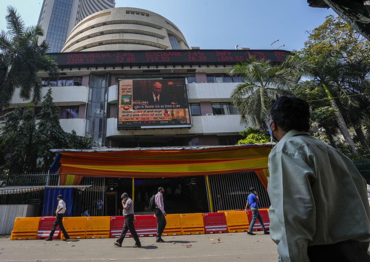 FILE - A man watches a screen showing Russian President Vladimir Putin on the facade of the Bombay Stock Exchange (BSE) building in Mumbai, India, Thursday, Feb. 24, 2022. India’s central bank on Wednesday, May 4, raised its key interest rate to 4.4% from 4% to contain fast-rising inflation. Reserve Bank of India Governor Shaktikanta Das expressed concern that the deteriorating global situation amid the war in Ukraine was causing a ``tectonic shift'' in commodity markets, trade and financial linkages. (AP Photo/Rafiq Maqbool, File)