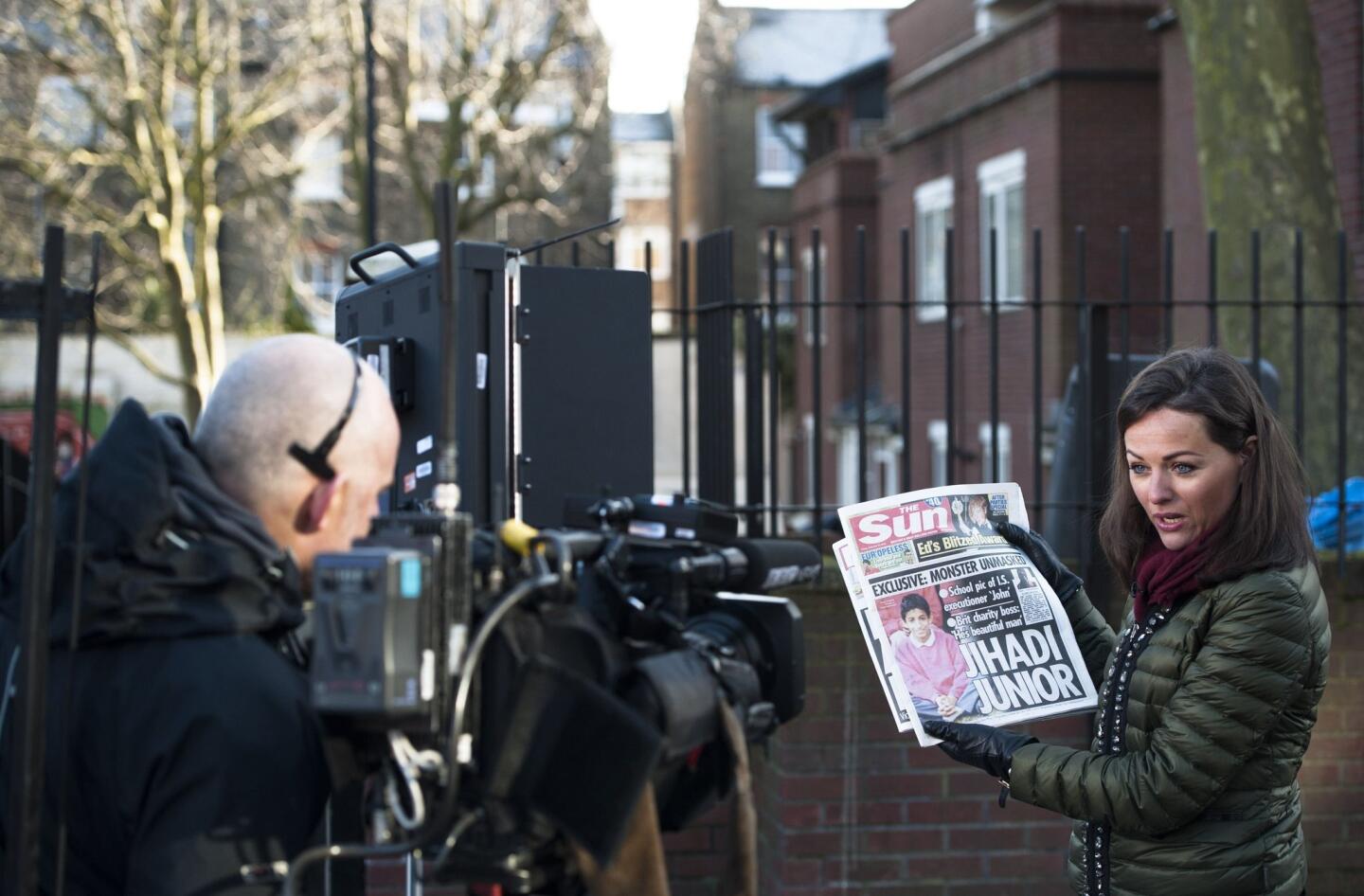 A journalist holds up a newspaper on Feb. 27 as she does a report outside a residence in London where Mohammed Emwazi, identified as the masked Islamic State militant "Jihadi John," is believed to have lived.
