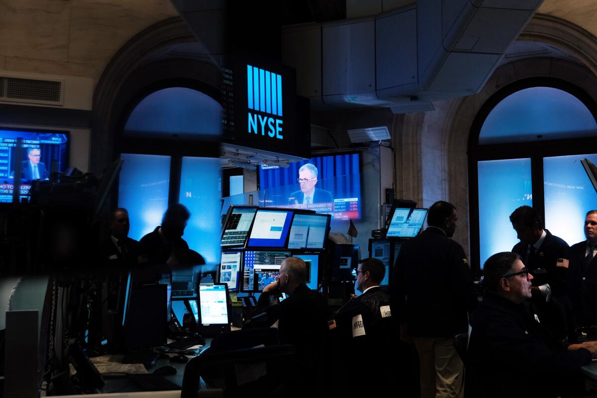 Federal Reserve Chairman Jerome H. Powell shown on a TV screen as traders work on the floor of the New York Stock Exchange.