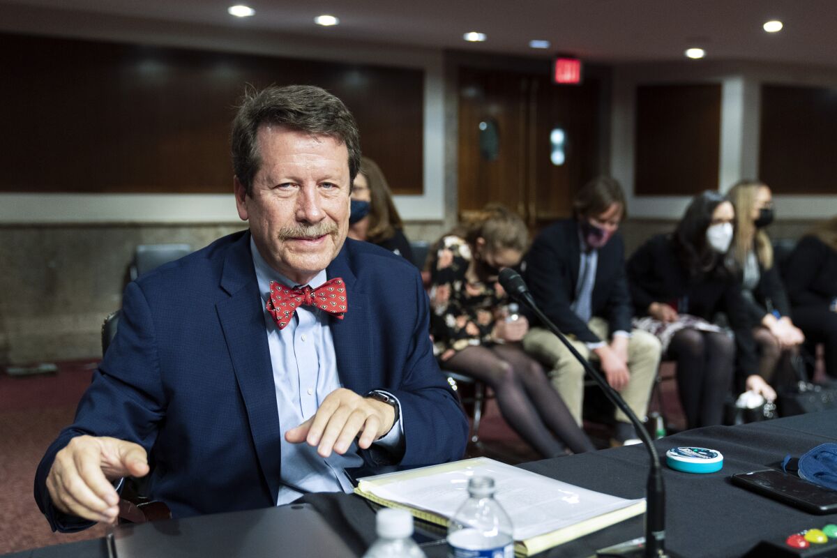 A seated and smiling Robert Califf gathers his documents as a Senate committee adjourns in Washington.