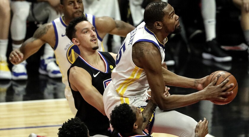 Warriors forward Kevin Durant slips past Clippers defenders for a layup during the second quarter of Game 4 on Sunday.