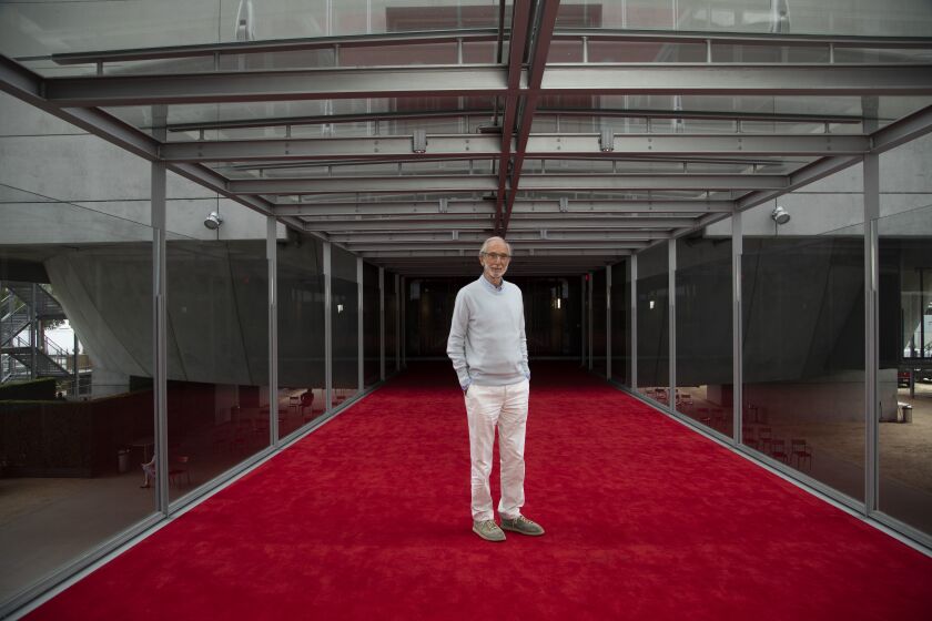 Renzo Piano, in a powder blue crewneck sweater, stands on the red carpet on the bridge of the Academy Museum