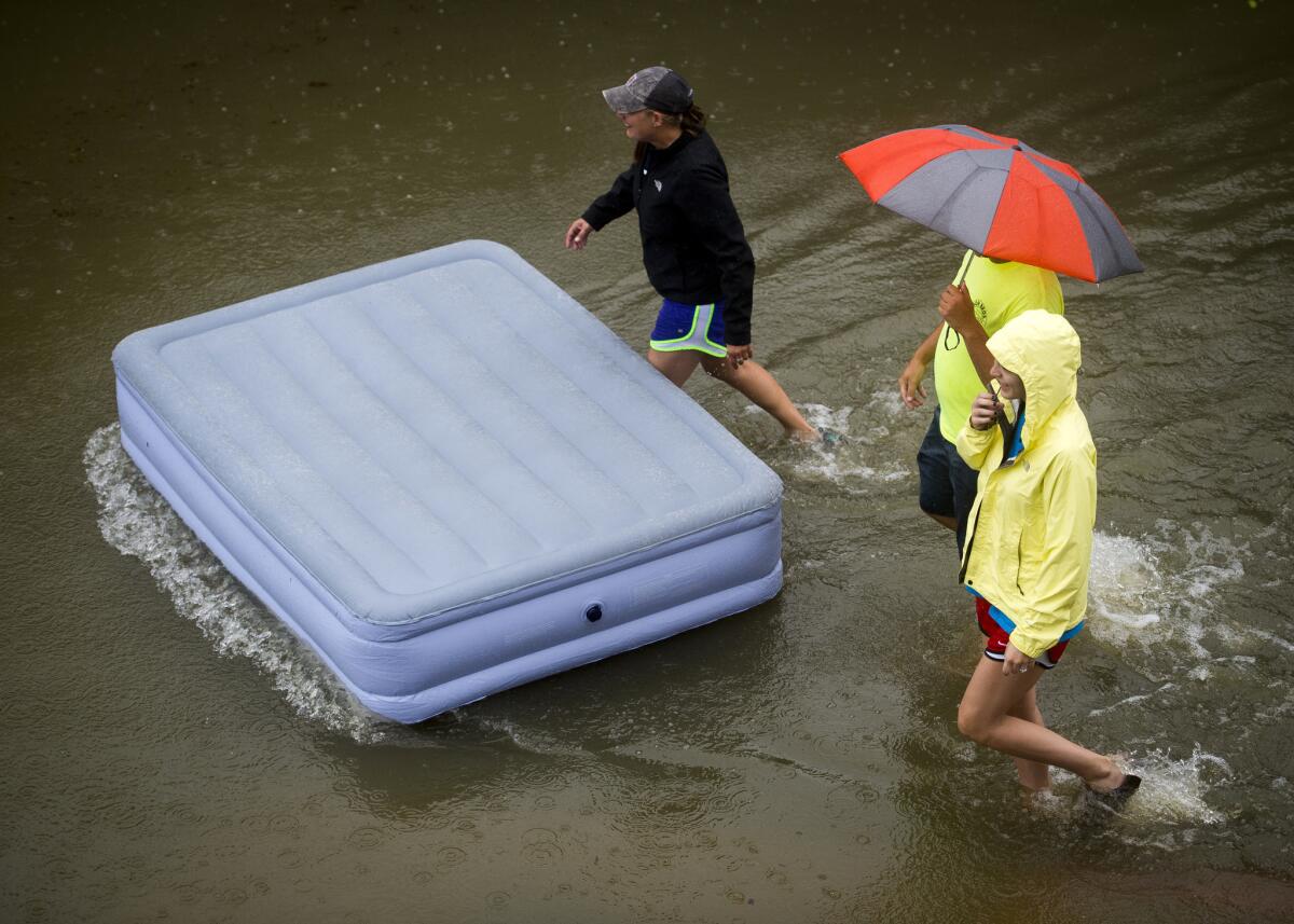 Residents push an inflatable mattress through flood water at Tiger Manor Apartments by the North Gates of Louisiana State University in Baton Rouge, La.