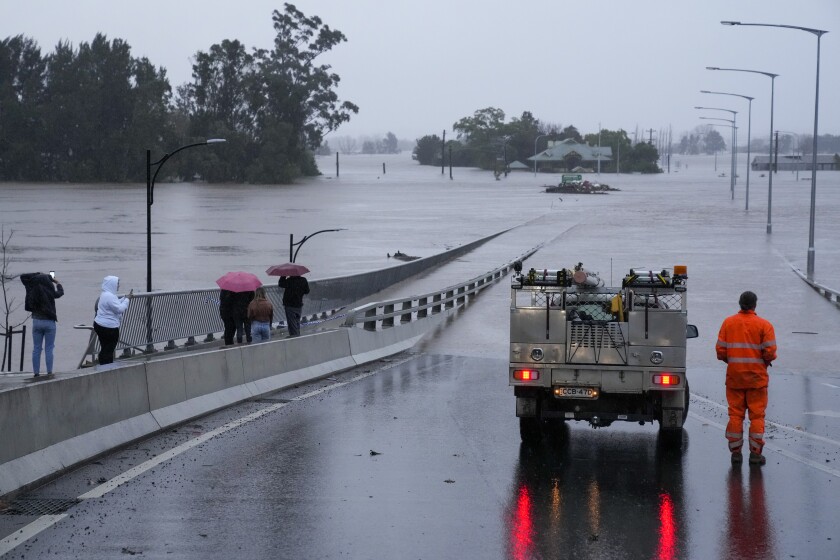 An emergency vehicle blocks access to the flooded Windsor Bridge on the outskirts of Sydney, Australia, Monday, July 4, 2022. More than 30,000 residents of Sydney and its surrounds have been told to evacuate or prepare to abandon their homes on Monday as Australia's largest city braces for what could be its worst flooding in 18 months. (AP Photo/Mark Baker)