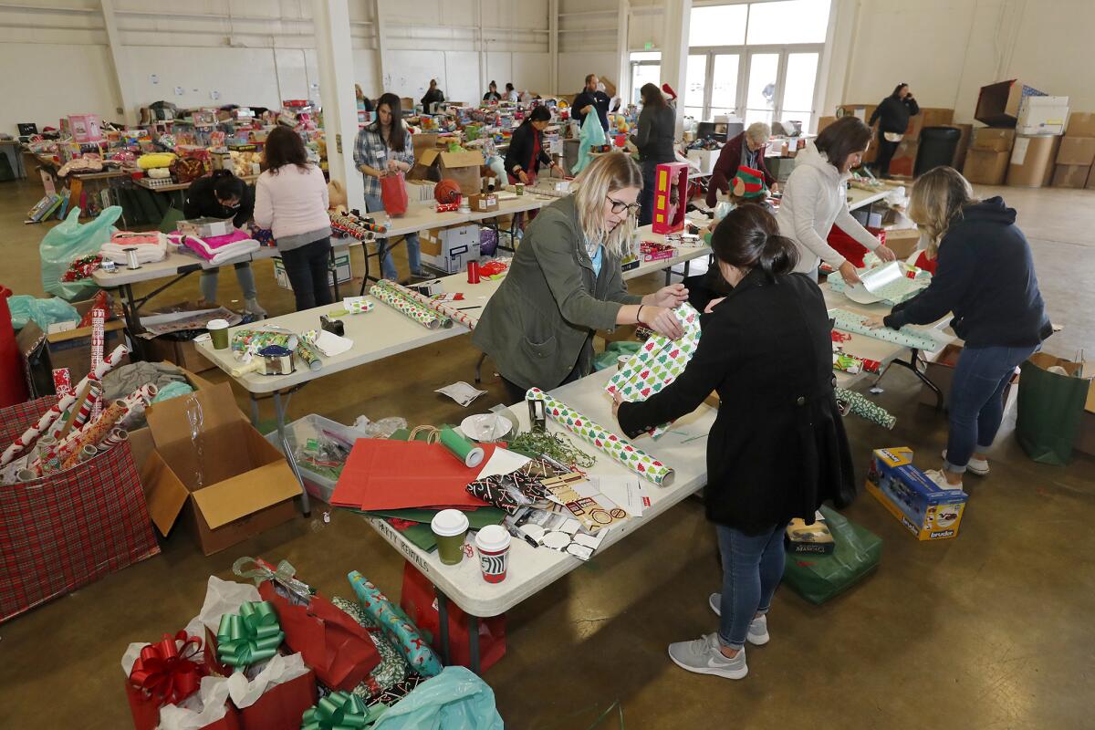 Volunteers wrap donated gifts at the OC Fair & Event Center for Share Our Selves' 50th annual Adopt A Family program, which helps struggling Orange County families for the holidays.