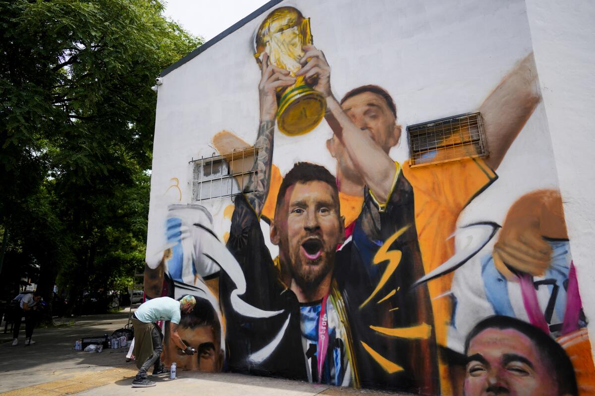 El artista Maxi Bagnasco pinta su mural con la imagen del astro Lionel Messi alzando la Copa de Mundo 