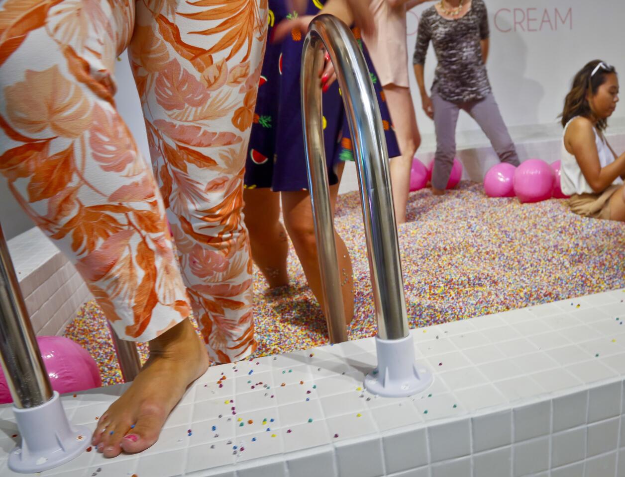 Visitors walk into a large pool filled with faux confetti-colored sprinkles, the biggest attraction of ice cream-themed works of art previewed at the Museum of Ice Cream on Thursday.