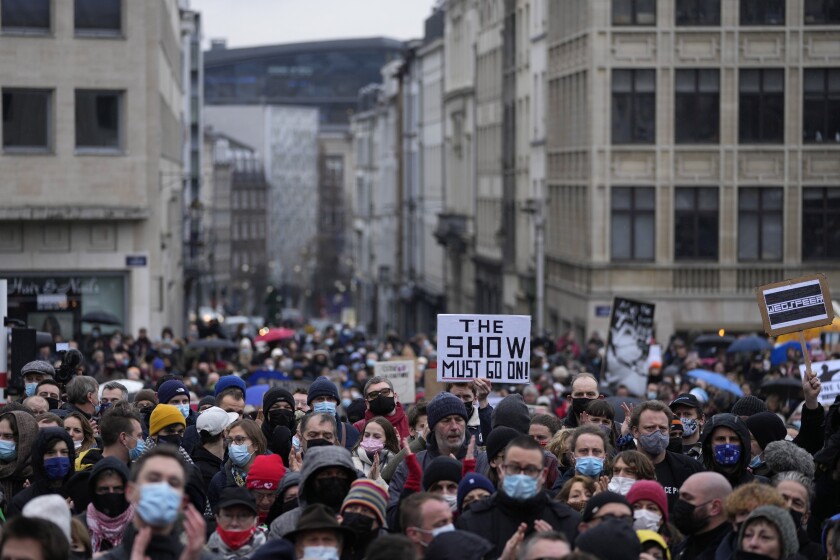 FILE - A man holds a sign which reads 'The show must go on' as he protests with other artists during a demonstration in Brussels on Sunday, Dec. 26, 2021. Belgian authorities allowed for the reopening of cinemas, theaters and concert halls on Wednesday, Dec. 29, 2021, handing a victory to the culture sector which challenged the latest COVID-19 rules that it felt unfairly targeted by. (AP Photo/Virginia Mayo, File)