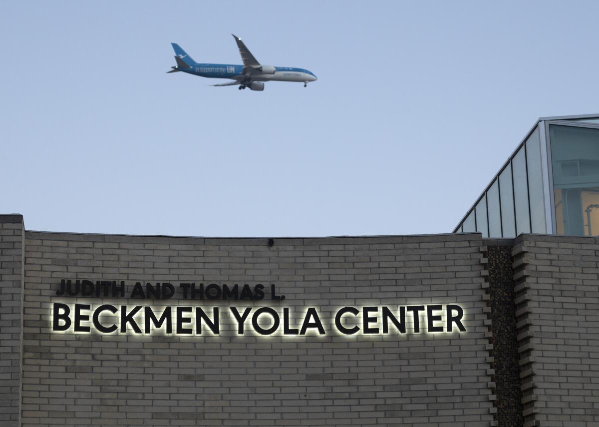 A plane flies over a building.