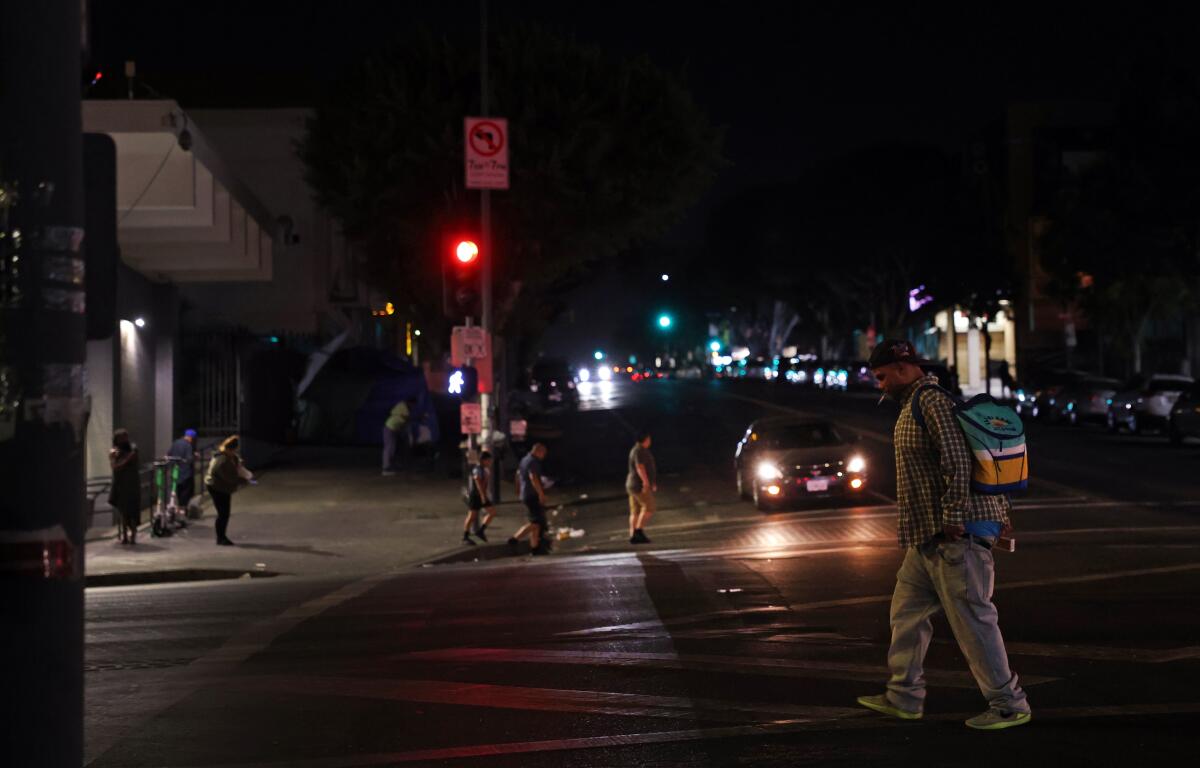  A streetlight is off at night as people walk by MacArthur Park in Los Angeles on Sept. 10. 