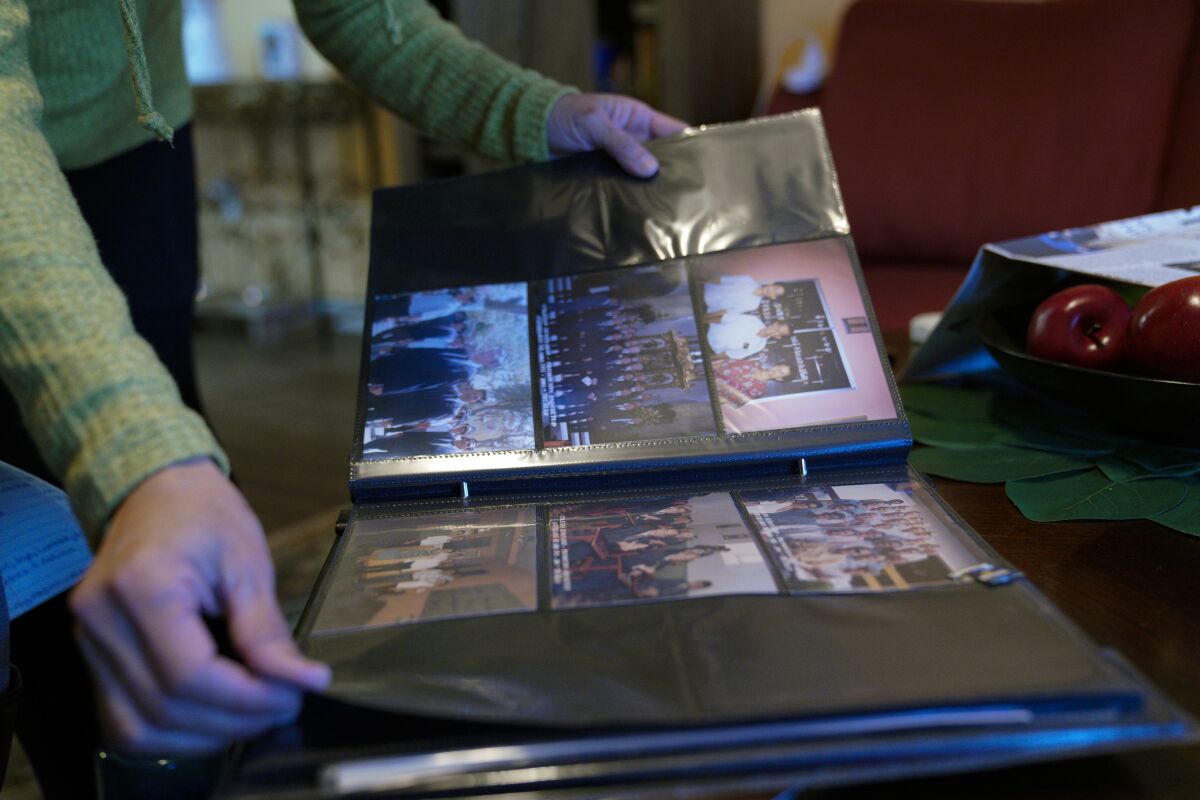 At her home in Santee, Carmen Kcomt looks over her family photo album. Kcomt fled to the U.S. from Peru in the early 2000s