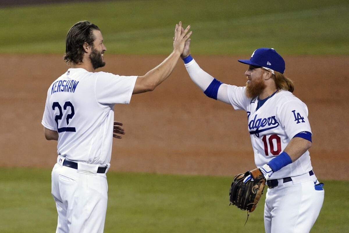 Dodgers starting pitcher Clayton Kershaw, left, high-fives Justin Turner after a playoff win over the Milwaukee Brewers.