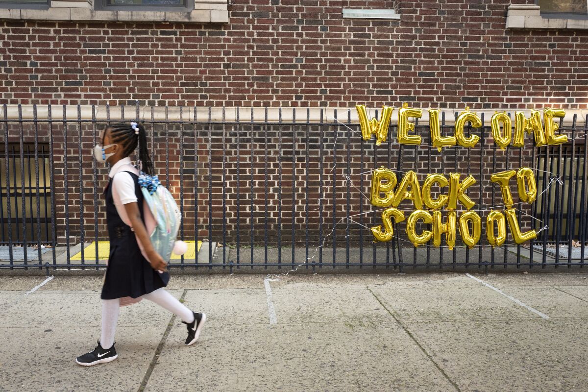 A girl in uniform passes a "Welcome Back to School" sign as she arrives for the first day of class