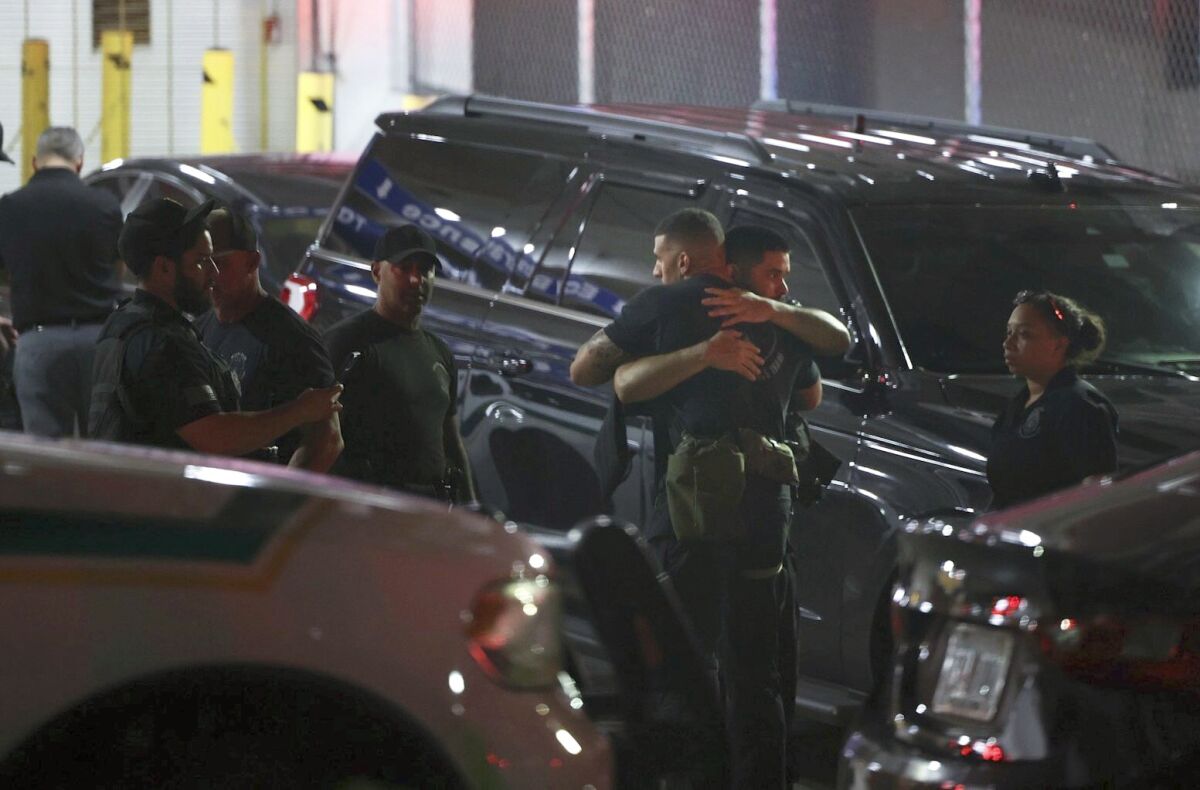 Police officers and other officials embrace while standing outside the Ryder Trauma Center after a Miami-Dade police officer was shot in an exchange of gunfire during a car chase with an armed robbery suspect, Monday, Aug. 15, 2022, in Miami. (Alie Skowronski/Miami Herald via AP)