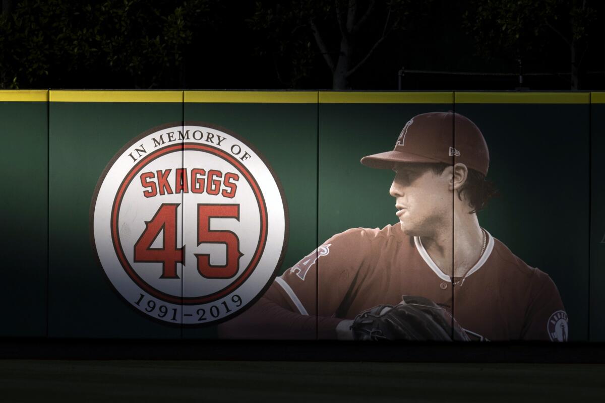 FILE - In this July 17, 2019, file photo, an image and logo memorializing former Los Angeles Angels pitcher Tyler Skaggs are displayed on the outfield wall in Anaheim, Calif. A California judge is allowing a lawsuit to proceed against the Angels over the drug-related death of Skaggs. (AP Photo/Kyusung Gong, File)
