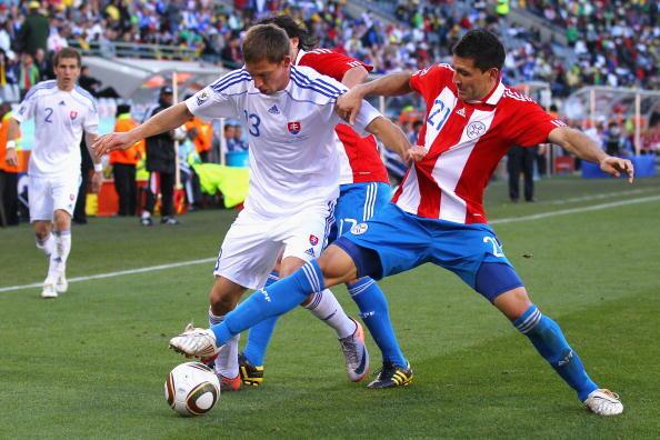 Antolin Alcaraz of Paraguay tackles Filip Holosko of Slovakia during the 2010 FIFA World Cup South Africa Group F match between Slovakia and Paraguay at the Free State Stadium on June 20, 2010 in Mangaung/Bloemfontein, South Africa.