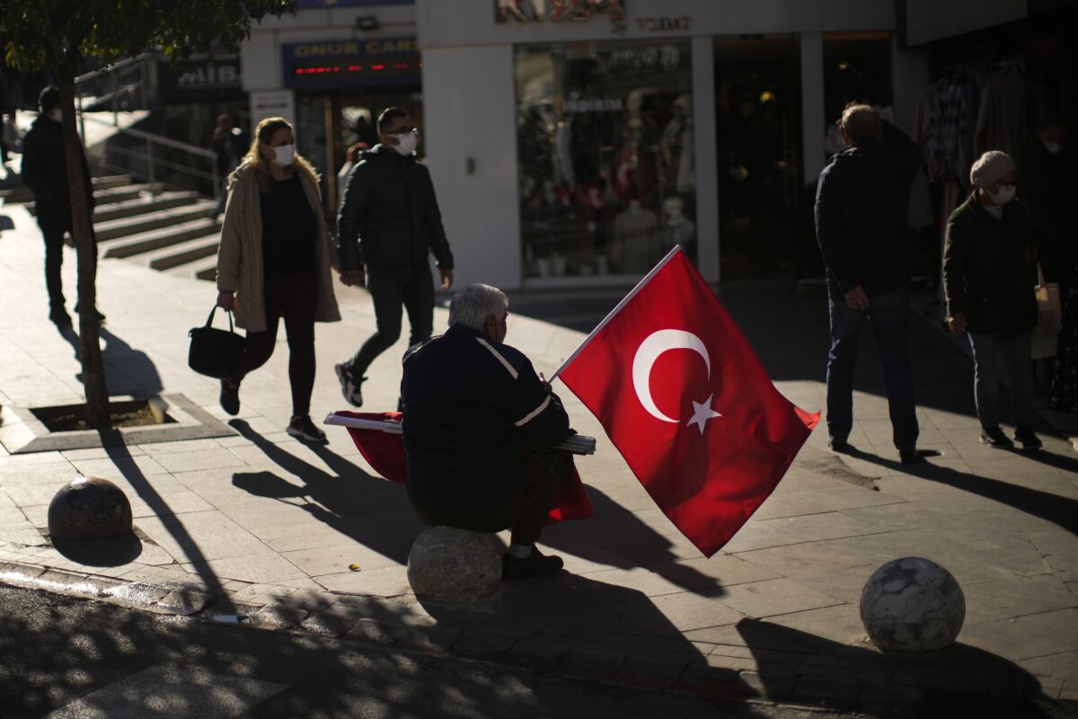 A man sells Turkish flags in a commercial area in Kadikoy neighbourhood in Istanbul, Turkey, Thursday, Dec. 2, 2021. Turkey’s beleaguered currency has been plunging to all-time lows against the U.S. dollar and the euro in recent months as President Recep Tayyip Erdogan presses ahead with a widely criticized effort to cut interest rates despite surging consumer prices. (AP Photo/Francisco Seco)
