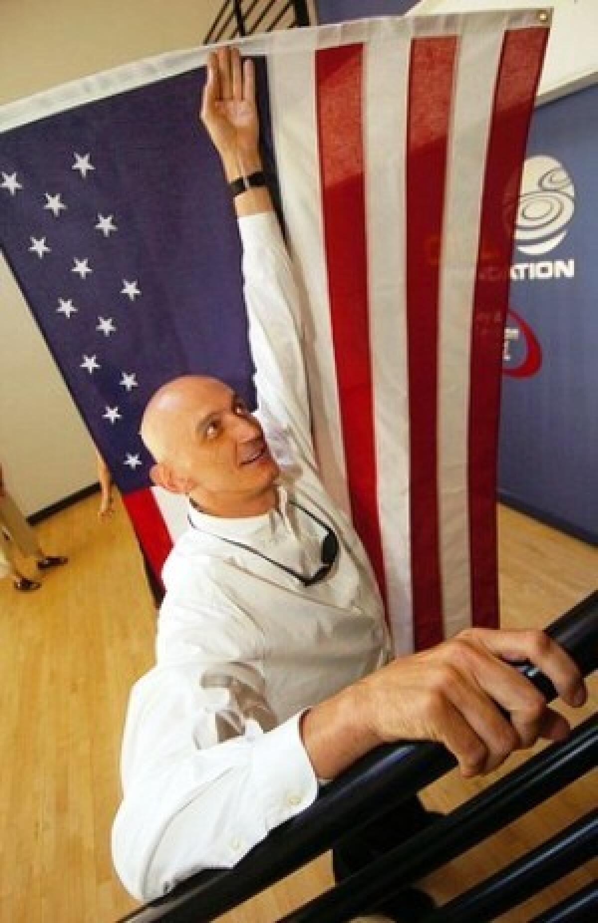 Rodger McFarlane, executive director of the Gill Foundation, hoists a replica of an American flag that he said carries only 14 stars to represent the states that protect gays and lesbians from job discrimination.