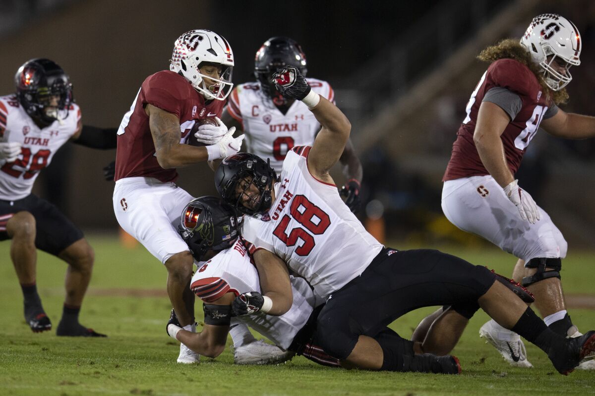 Stanford running back Austin Jones is stopped for a loss by Utah defenders Cole Bishop and Junior Tafuna.