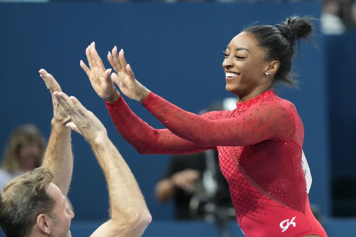 Simone Biles celebrates with her coach after competing in the Paris Olympics vault final Saturday.