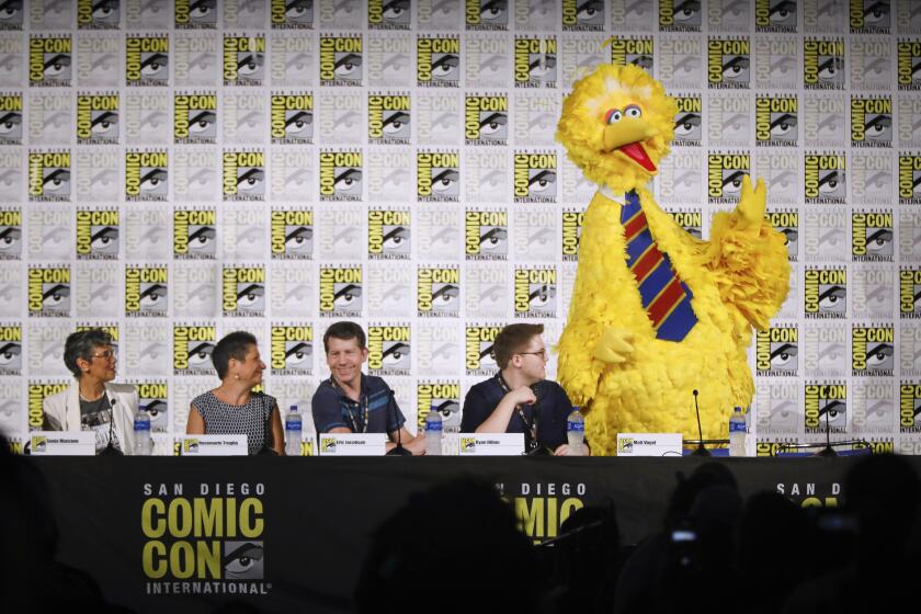 Sesame Street actor and puppeteer Matt Vogel, right, in character as Big Bird, introduces the panelists for the Sesame Street at 50 panel discussion, Sonia Manzano, left, who played Maria, Dr. Rosemarie Truglio, senior vice president of Sesame Workshop Content, Eric Jacobson, who is Grover, Bert and Oscar, and Ryan Ryan Dillon, who is Elmo, on day three of the Comic-Con International Convention, July 20, 2019, at the San Diego Convention Center, in San Diego, California.