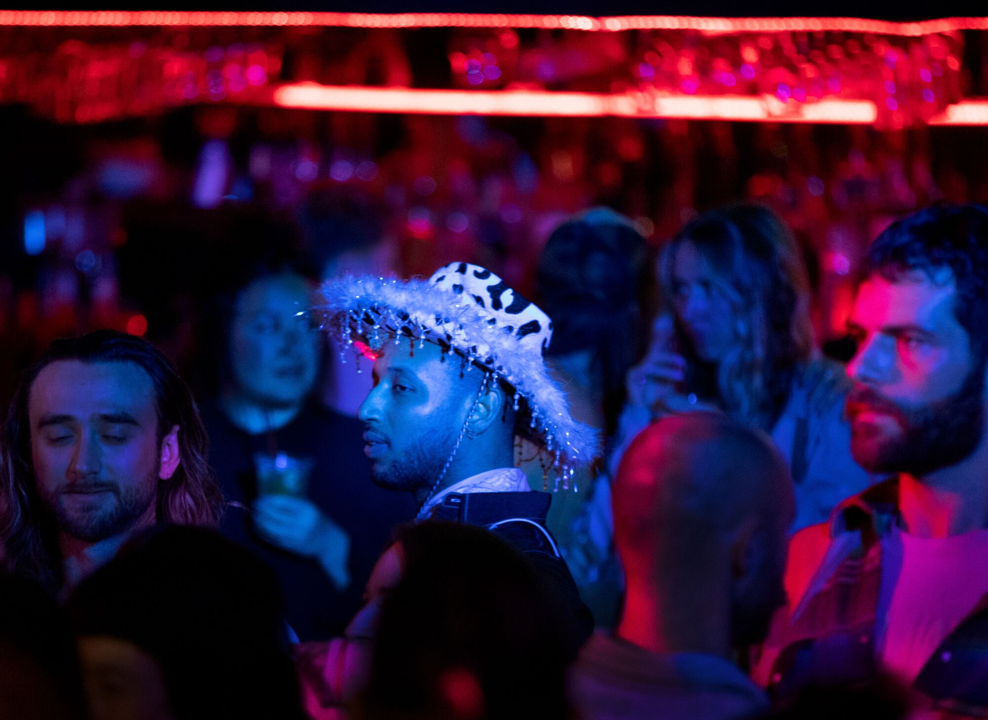 A person wearing a decorative western hat joins the crowd watching people dance together at Stud Country.