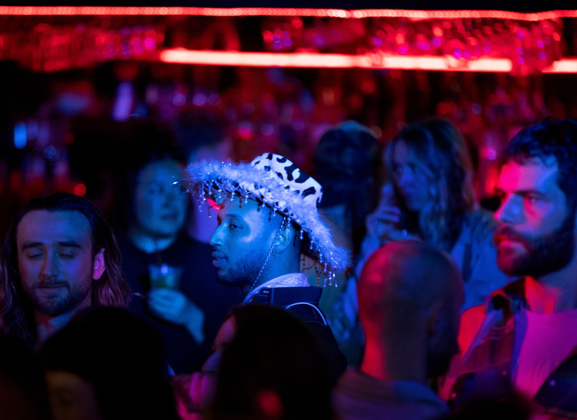 Une personne portant un chapeau western décoratif se joint à la foule en regardant les gens danser ensemble au Stud Country.