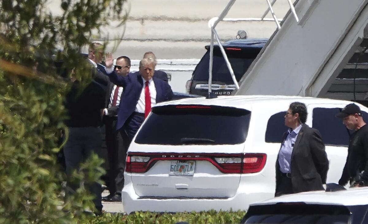 El expresidente Donald Trump saluda antes de abordar su avión en el Aeropuerto Internacional de Palm Beach