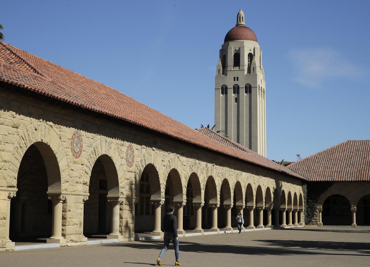 People walk on the Stanford University campus beneath Hoover Tower.