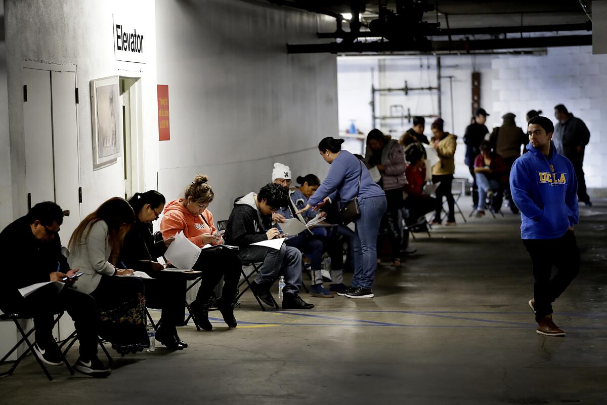 Workers hunch over paperwork as they apply for unemployment benefits. 