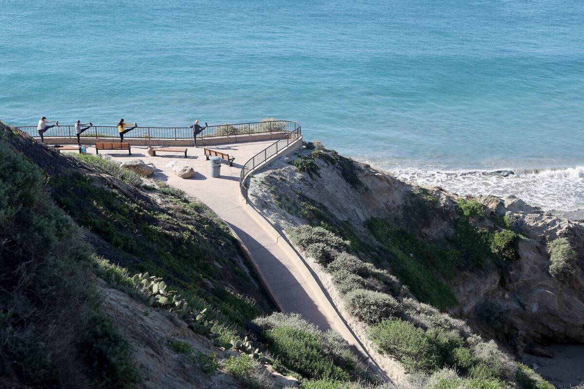 A group of women stretch their leg on a railing along the lower path at Inspiration Point.