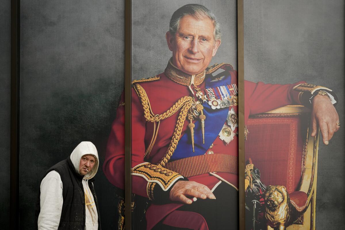A man walks by a portrait of King Charles III in London.