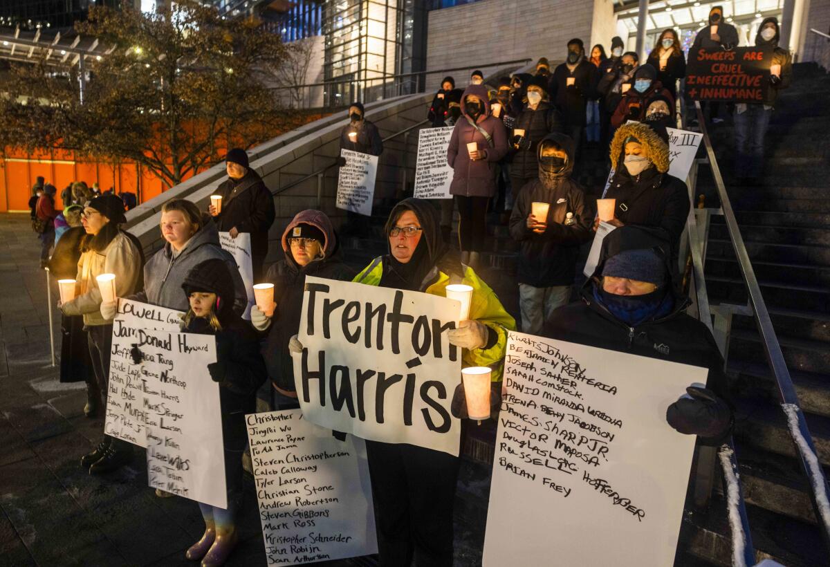 Jennifer Dobbins, center, holds a name of her son Trenton Harris at a Women in Black solstice vigil remembering the homeless who died in 2022, outside of Seattle City Hall on Dec. 21, 2022. Harris was 30-years-old when he was shot four times and killed in July of last year. His death was ruled a homicide by the King County Medical Examiner's Office. (Daniel Kim/The Seattle Times via AP)