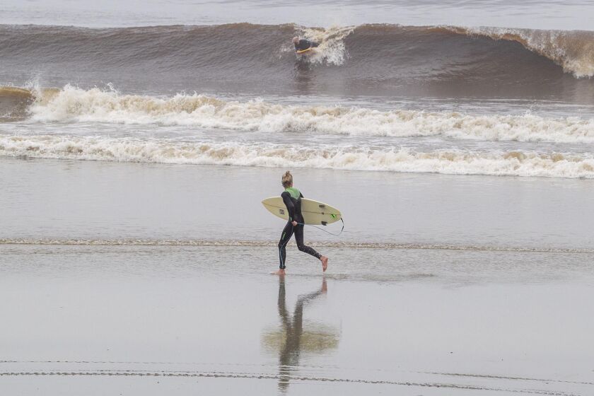 An eager surfer sprinted down Moonlight Beach. The City of Encinitas reopened their beaches in a limited manner at 8:00 am on Monday, April 27, 2020 on a limited basis. They are trying to channel all beach users through the Moonlight Beach Park.